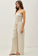 Load image into Gallery viewer, Woman wearing a beige strapless top and wide-leg pants on a white background