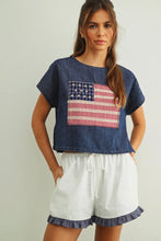 Load image into Gallery viewer, Woman wearing a denim top with an American flag design and white shorts on a plain background