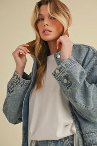 Woman wearing a denim jacket over a white shirt on a beige background