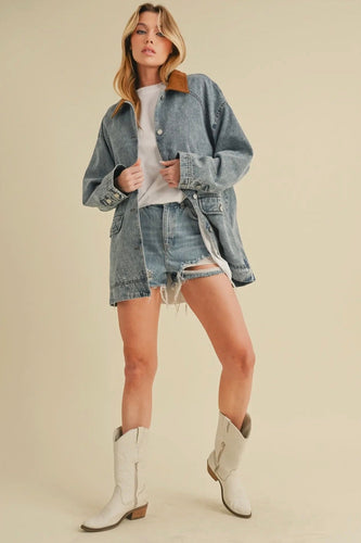 Woman wearing a denim jacket, white shirt, shorts, and white cowboy boots on a beige background