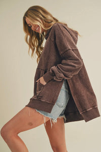 Woman wearing a brown hoodie and denim shorts on a plain background