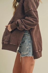 Person wearing a brown jacket and denim shorts on a plain background