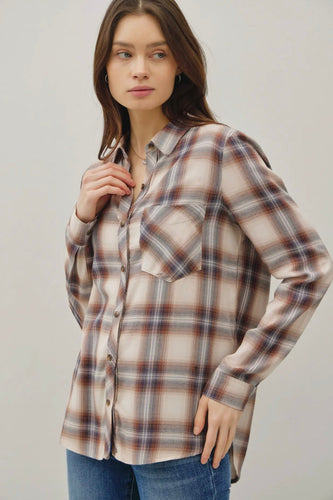 Woman wearing a plaid shirt and jeans against a plain background
