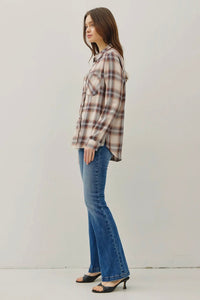 Woman wearing a plaid shirt and blue jeans on a plain background