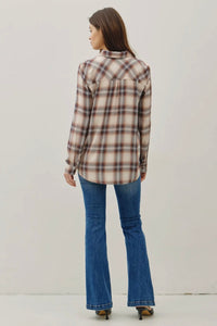 Woman wearing a plaid shirt and blue jeans against a plain background