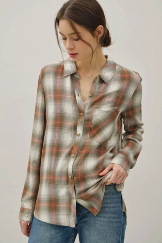 Woman wearing a plaid shirt and jeans on a plain background