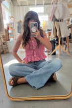 Load image into Gallery viewer, Person sitting on the floor in a clothing store, wearing a red checkered top and blue jeans.