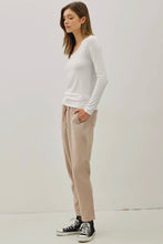 Load image into Gallery viewer, Woman wearing a white long-sleeve top and beige pants on a plain background