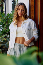 Load image into Gallery viewer, Woman wearing a white jacket and light skirt standing outdoors with plants around