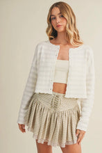 Load image into Gallery viewer, Woman wearing a white cardigan over a white top and patterned skirt on a beige background