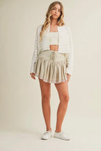 Load image into Gallery viewer, Woman wearing a white jacket, white top, and patterned skirt on a beige background