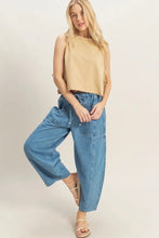 Load image into Gallery viewer, Woman wearing a beige sleeveless top and blue jeans on a plain background