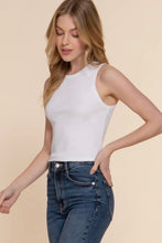 Load image into Gallery viewer, Woman wearing a white sleeveless top and blue jeans on a beige background