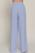Load image into Gallery viewer, Blue and white striped pants on a beige background