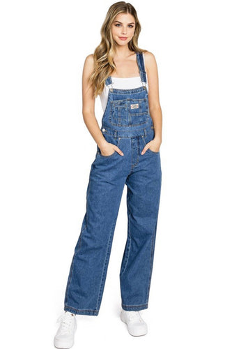 Woman wearing blue denim overalls on a white background