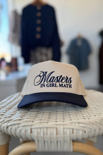 Cap with 'Masters in Girl Math' text on a wicker chair with blurred background