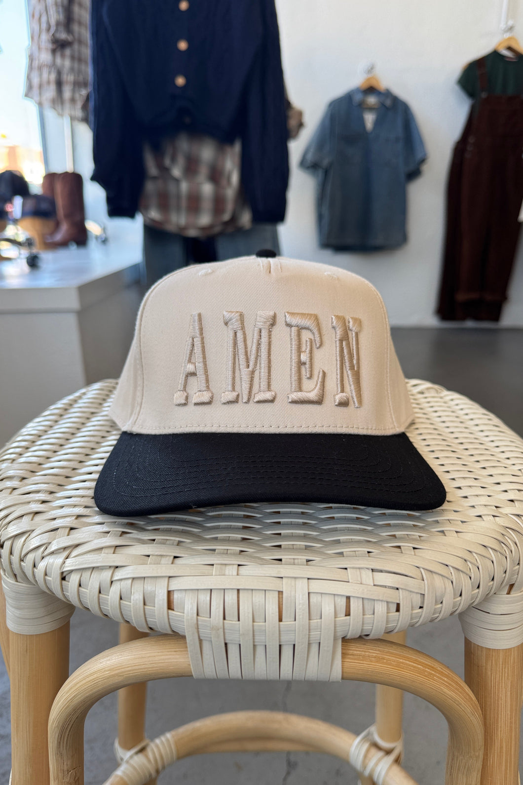 Wicker chair with 'ALMEN' branding in a clothing store setting