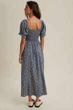 Load image into Gallery viewer, Woman wearing a blue floral dress on a beige background
