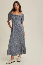 Load image into Gallery viewer, Woman wearing a blue floral dress on a beige background
