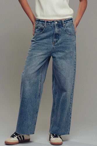 Person wearing blue jeans with a plain background