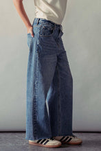Load image into Gallery viewer, Person wearing blue wide-leg jeans and a white top against a plain background
