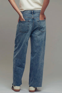 Person wearing blue jeans on a plain background