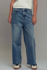Person wearing blue jeans and a white top on a plain background