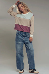 Person wearing a color-blocked sweater and jeans on a plain background