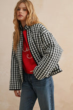 Load image into Gallery viewer, Woman wearing a black and white checkered jacket over a red sweater and blue jeans on a beige background