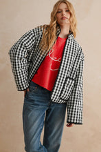 Load image into Gallery viewer, Woman wearing a red graphic t-shirt, blue jeans, and a black and white checkered jacket on a beige background
