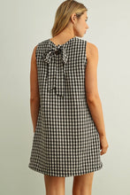 Load image into Gallery viewer, Woman wearing a black and white checkered dress with a tie back on a plain background