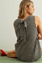 Load image into Gallery viewer, Woman wearing a black and white checkered dress with a bow detail on a light background