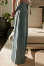 Load image into Gallery viewer, Person wearing light blue jeans standing in a living room.