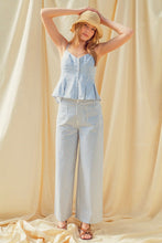 Load image into Gallery viewer, Woman wearing a blue striped top and pants with a straw hat against a beige curtain background