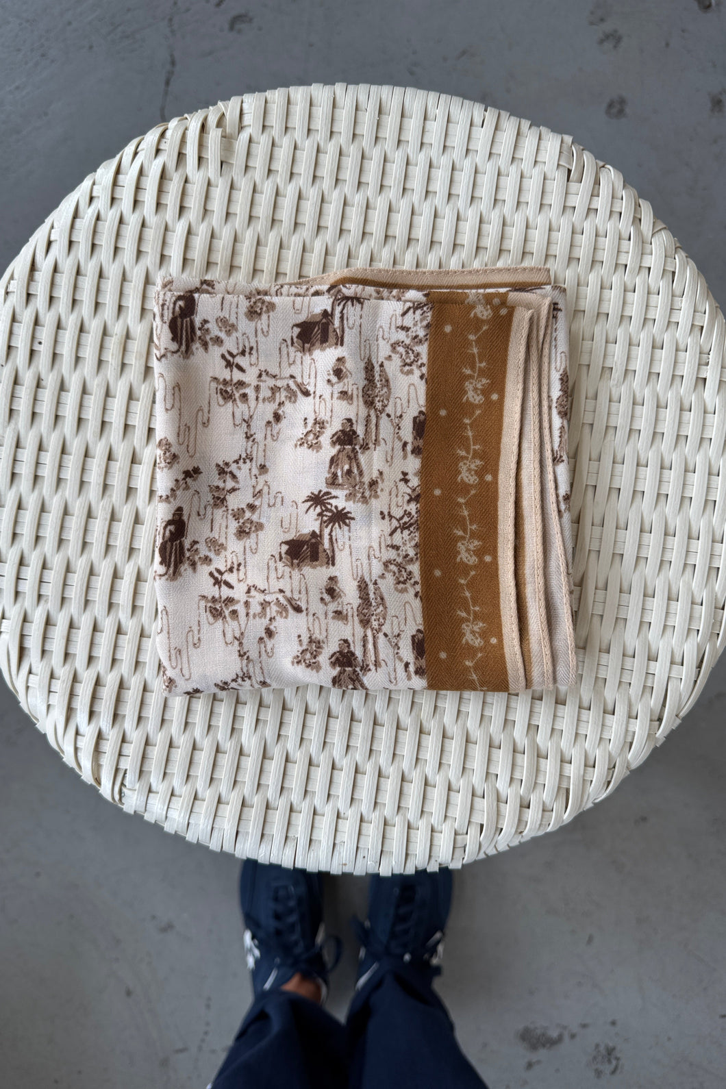 Round woven basket with folded fabric inside on a concrete floor.
