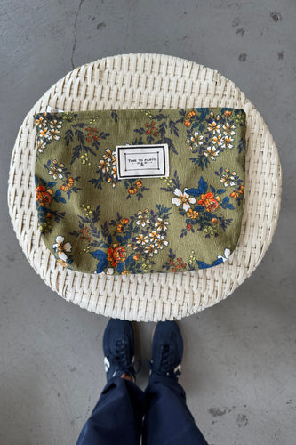 Round woven stool with floral patterned cushion on a concrete floor