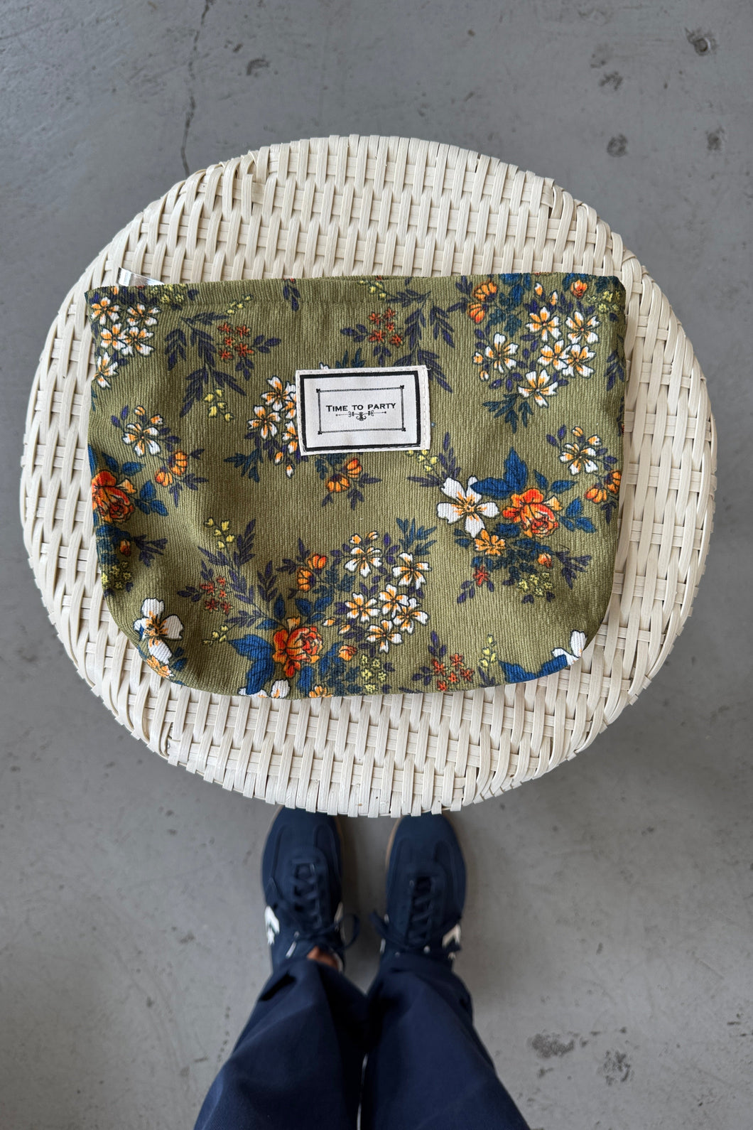 Round woven stool with floral patterned cushion on a concrete floor