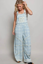 Load image into Gallery viewer, Woman wearing a checkered overalls with rolled-up sleeves on a plain background