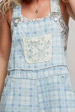 Load image into Gallery viewer, Light blue checkered overalls with a floral pocket on a neutral background