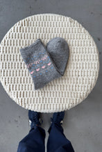 Load image into Gallery viewer, Gray socks with pink patterns on a woven stool against a concrete floor.