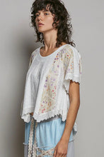 Load image into Gallery viewer, Woman wearing a floral lace top and light blue pants against a gray background