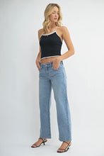 Load image into Gallery viewer, Woman wearing a black top and light blue jeans on a white background