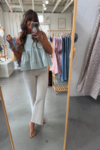 Load image into Gallery viewer, Person taking a mirror selfie wearing a light green top and beige pants in a clothing store.