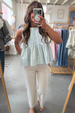 Load image into Gallery viewer, Woman taking a mirror selfie wearing a light green top and white pants in a clothing store.