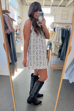 Load image into Gallery viewer, Woman taking a mirror selfie wearing a floral dress and black boots in a clothing store.