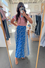 Load image into Gallery viewer, Person wearing a blue floral skirt and pink top in a clothing store.