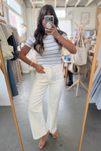 Load image into Gallery viewer, Woman taking a mirror selfie wearing a striped shirt and white pants in a clothing store.