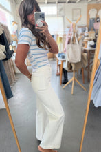 Load image into Gallery viewer, Woman taking a mirror selfie wearing a striped shirt and white pants in a store.