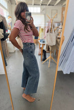 Load image into Gallery viewer, Person taking a mirror selfie wearing a striped shirt and jeans in a store.