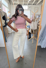 Load image into Gallery viewer, Person taking a mirror selfie wearing a striped shirt and white pants in a store.